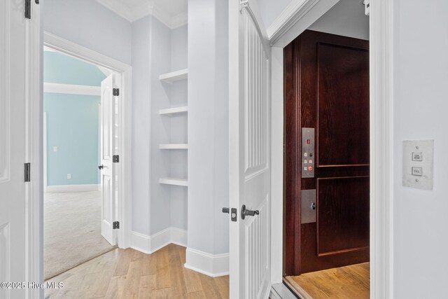 unfurnished living room featuring baseboards, wood-type flooring, ornamental molding, and a fireplace