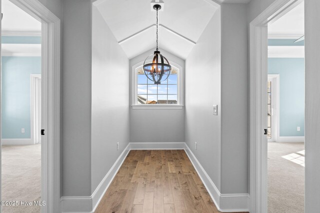 hallway featuring built in shelves, baseboards, light colored carpet, elevator, and light wood-style floors