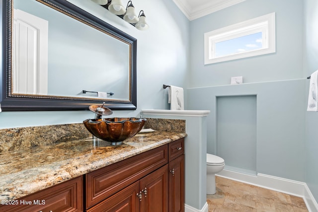 bathroom featuring baseboards, toilet, ornamental molding, and vanity