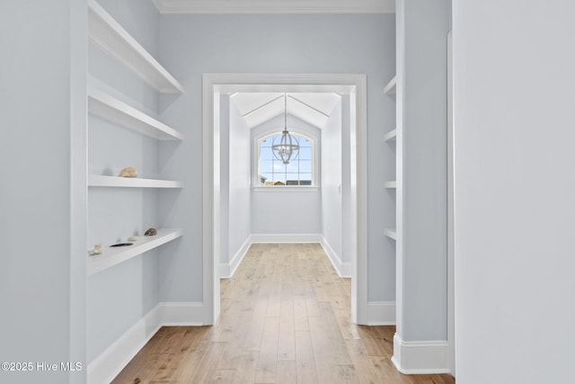 walk in closet with a notable chandelier and wood finished floors