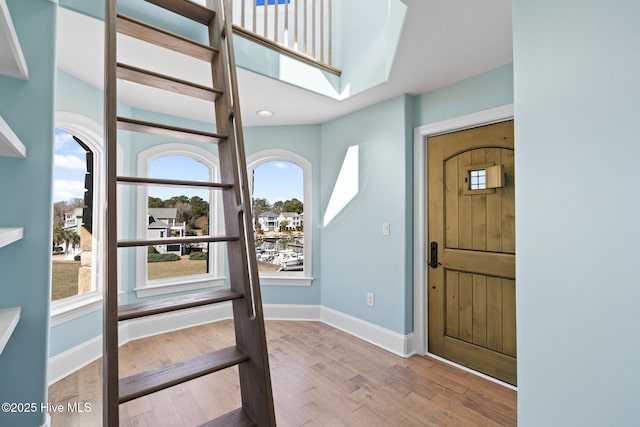 foyer with a skylight, wood finished floors, and baseboards