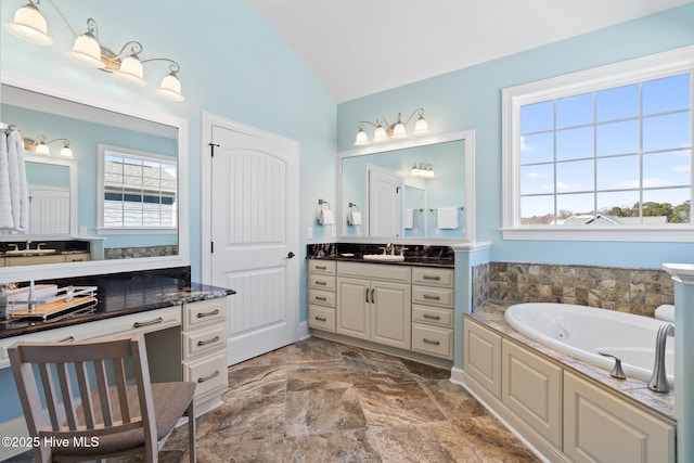 full bath featuring vanity, lofted ceiling, a tub with jets, and a wealth of natural light