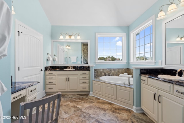 bathroom featuring a sink, lofted ceiling, two vanities, and a bath