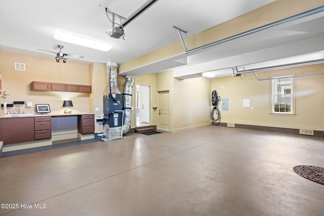 garage featuring heating unit, visible vents, baseboards, a sink, and a garage door opener