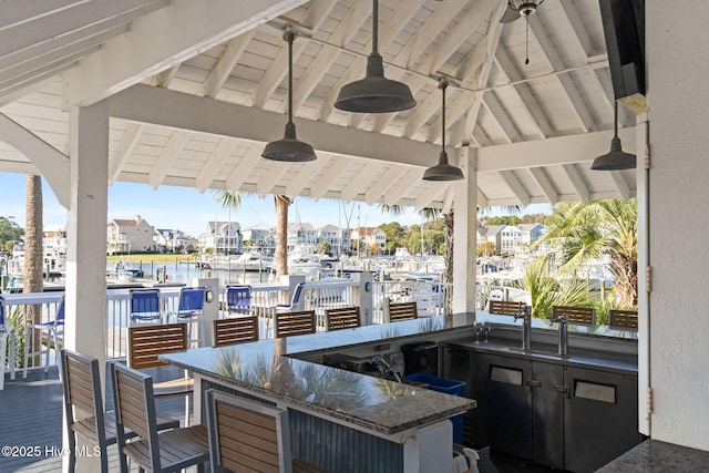 view of patio / terrace featuring a gazebo, outdoor wet bar, ceiling fan, and a water view