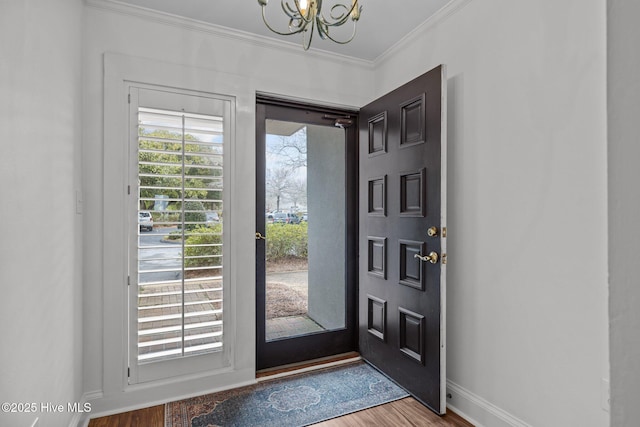 entryway featuring hardwood / wood-style flooring, crown molding, and a notable chandelier