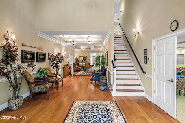 entryway with crown molding, a tray ceiling, and light wood-type flooring