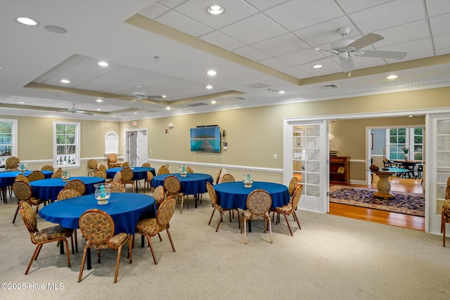 carpeted dining area featuring french doors, ceiling fan, and a tray ceiling