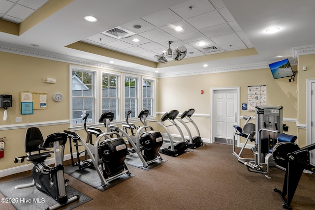 workout area with a raised ceiling and ornamental molding