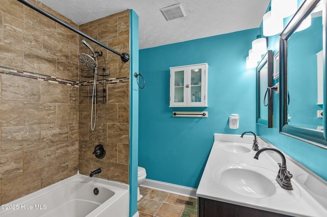 full bathroom with vanity, tiled shower / bath, toilet, and a textured ceiling