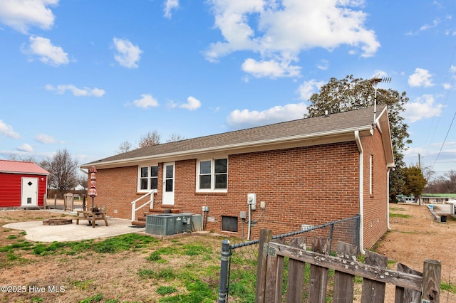 rear view of house with central AC unit, a patio, and an outdoor fire pit