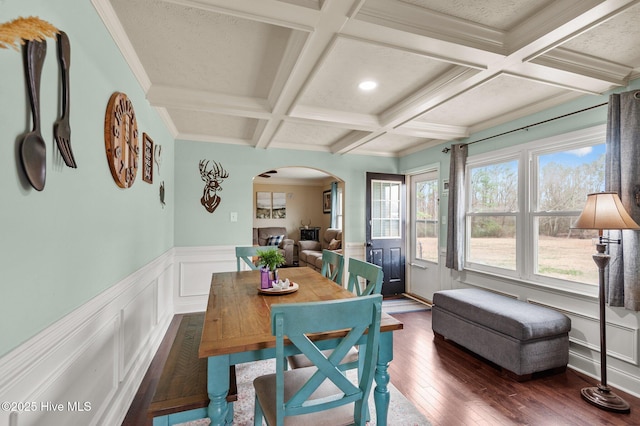 dining space featuring coffered ceiling, ornamental molding, dark hardwood / wood-style floors, and beam ceiling