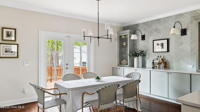 dining room featuring a notable chandelier, dark wood-type flooring, ornamental molding, and french doors