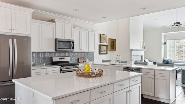 kitchen with stainless steel appliances, a center island, white cabinets, decorative backsplash, and kitchen peninsula