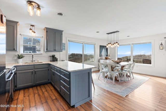 kitchen featuring range with electric cooktop, dark wood-style flooring, a sink, visible vents, and hanging light fixtures