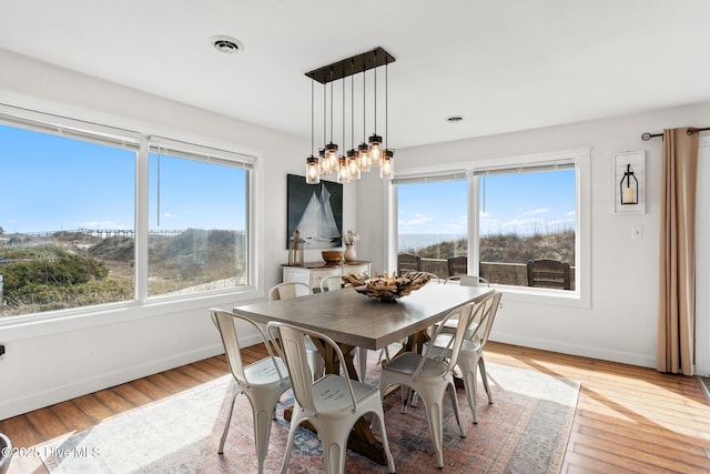 dining space featuring light wood-type flooring, visible vents, and baseboards