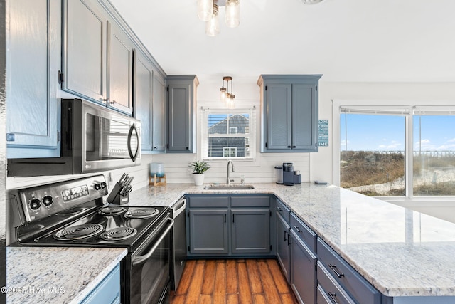 kitchen featuring light stone counters, stainless steel appliances, a sink, decorative backsplash, and dark wood-style floors