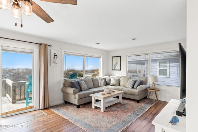 living room with wood-type flooring, a ceiling fan, and baseboards