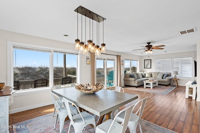 dining room featuring ceiling fan with notable chandelier, visible vents, baseboards, and wood finished floors