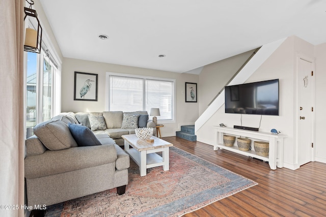 living room featuring wood finished floors, a healthy amount of sunlight, and stairs