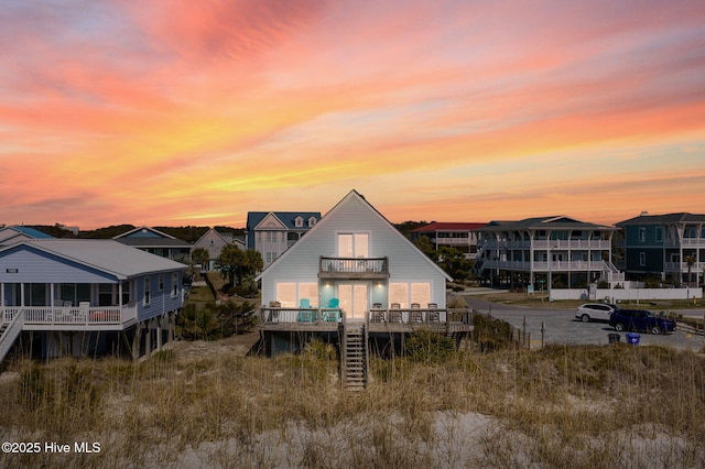 back of house at dusk with a balcony and stairway