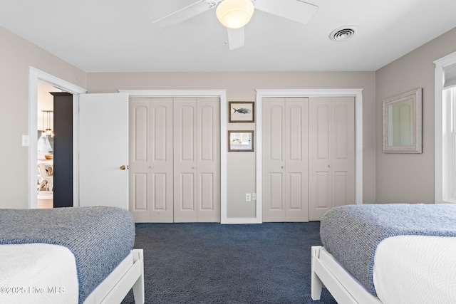 carpeted bedroom featuring visible vents, ceiling fan, and two closets