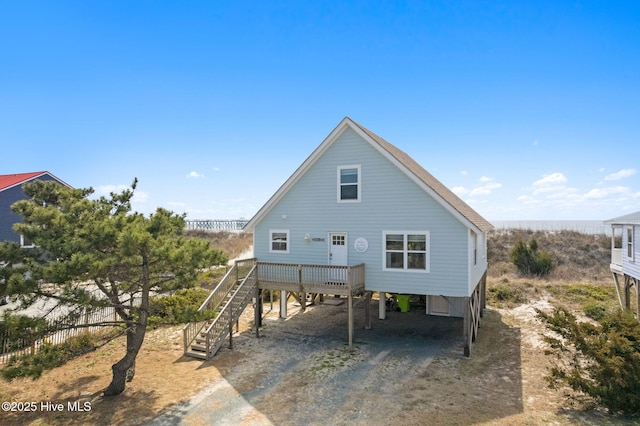 back of property featuring dirt driveway, stairway, and a carport