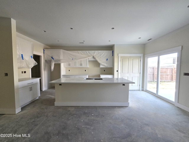 kitchen featuring an island with sink and white cabinets