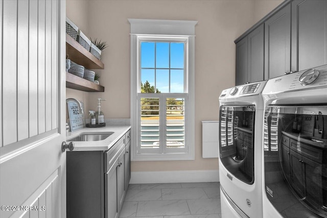 washroom with a sink, baseboards, washer and dryer, marble finish floor, and cabinet space