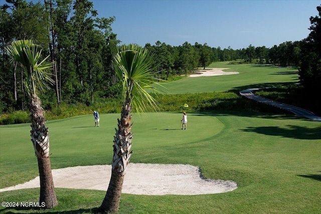 view of property's community with view of golf course and a yard