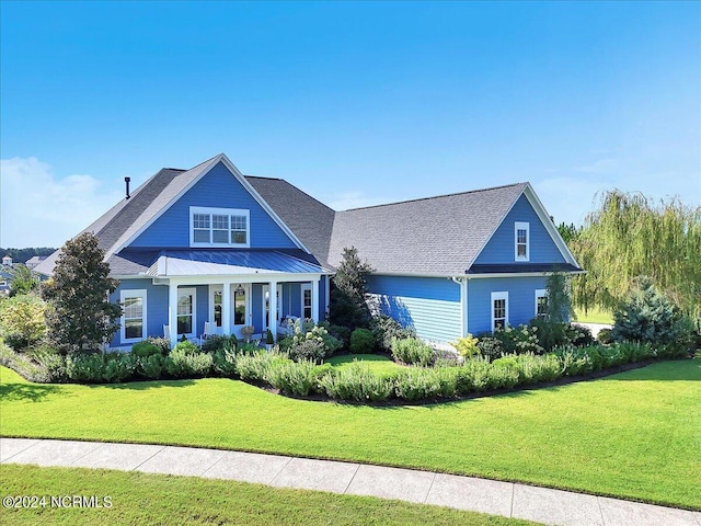 view of front of home with metal roof, a standing seam roof, a porch, and a front yard