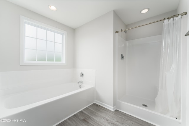 bathroom with wood-type flooring and shower with separate bathtub