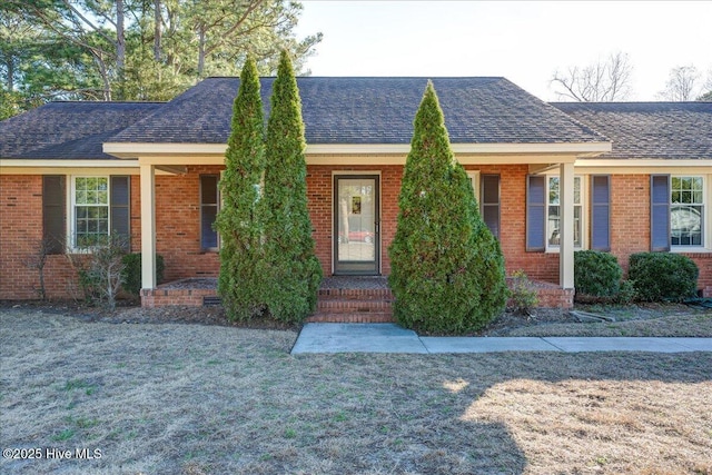 ranch-style home with brick siding, roof with shingles, and a front yard