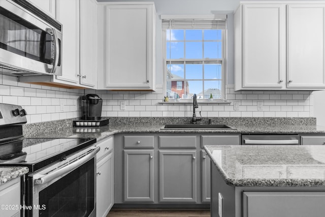 kitchen featuring appliances with stainless steel finishes, sink, white cabinets, and light stone counters