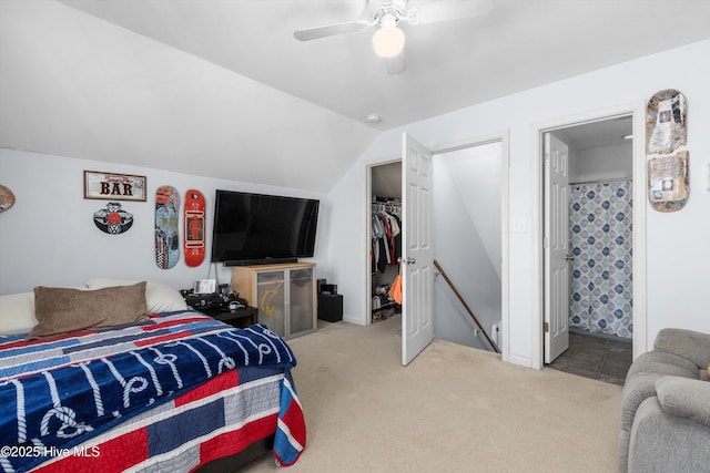 bedroom featuring lofted ceiling, ceiling fan, connected bathroom, light colored carpet, and a closet