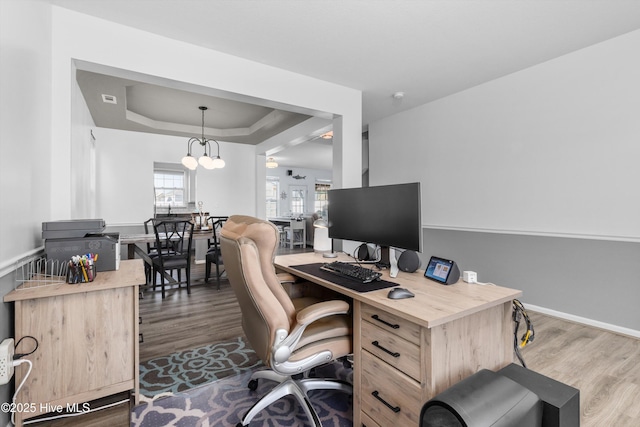 office area featuring hardwood / wood-style flooring, a tray ceiling, and a chandelier