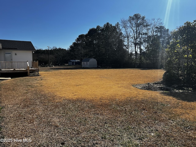 view of yard featuring a wooden deck and a storage shed