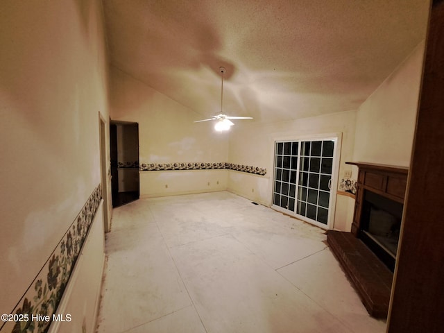 unfurnished living room featuring ceiling fan, vaulted ceiling, and a textured ceiling