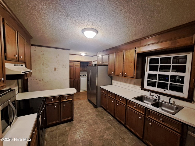 kitchen featuring sink, appliances with stainless steel finishes, dark brown cabinets, a textured ceiling, and washer / dryer