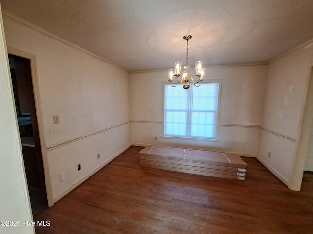 unfurnished dining area with ornamental molding, dark hardwood / wood-style flooring, a textured ceiling, and a notable chandelier