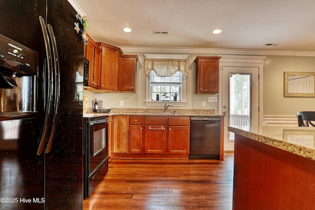 kitchen featuring light stone counters, dark wood finished floors, crown molding, visible vents, and black appliances