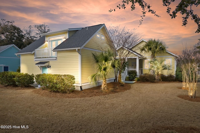 exterior space featuring a balcony and a shingled roof