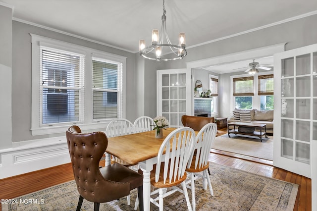 dining space with crown molding, ceiling fan with notable chandelier, and hardwood / wood-style floors