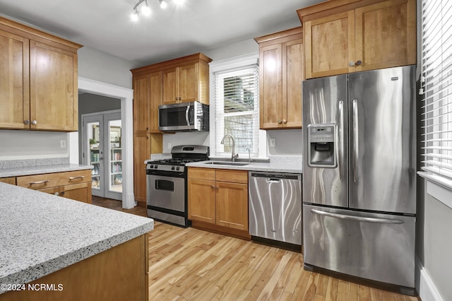 kitchen featuring track lighting, appliances with stainless steel finishes, sink, and light wood-type flooring