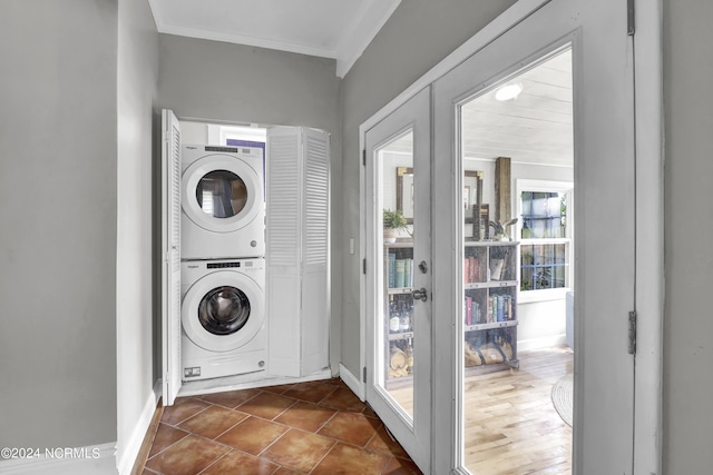 laundry room featuring ornamental molding, stacked washer / dryer, and dark tile patterned flooring