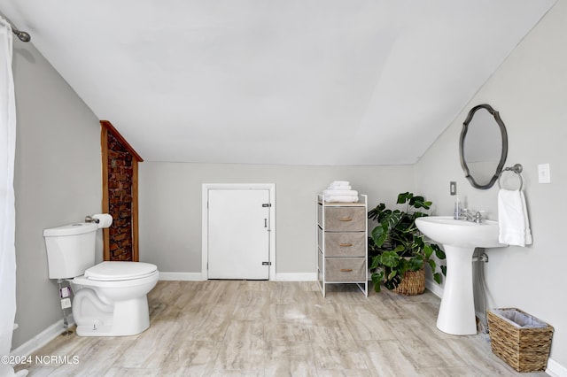 bathroom with lofted ceiling, wood-type flooring, and toilet