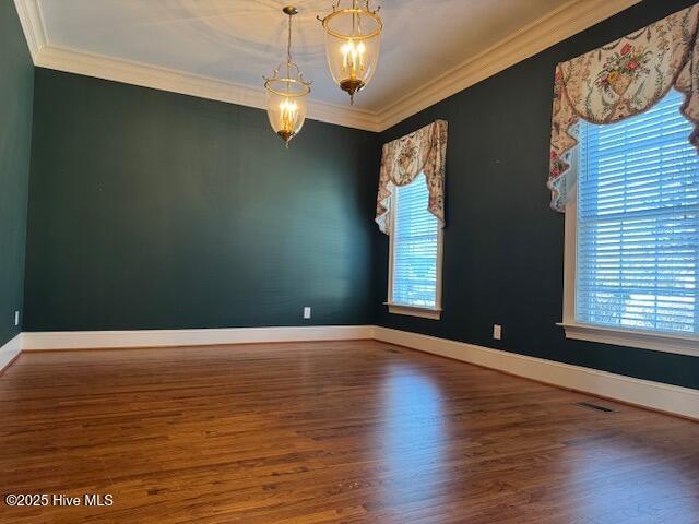 spare room with crown molding, dark hardwood / wood-style floors, and a chandelier