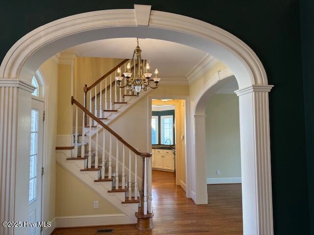 interior space featuring crown molding, hardwood / wood-style floors, and a notable chandelier