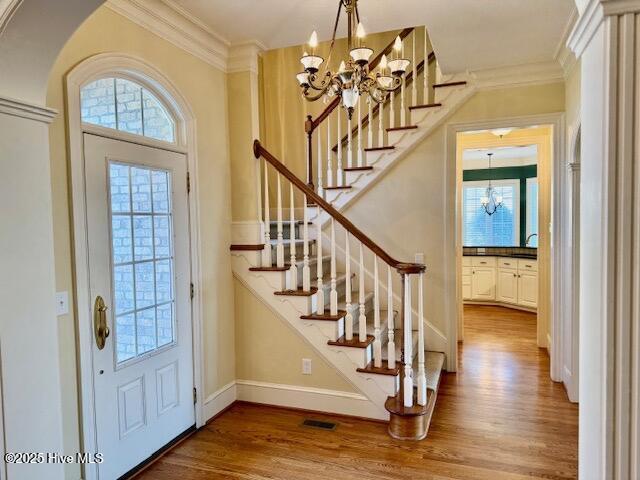 interior space with crown molding, wood-type flooring, sink, and a notable chandelier