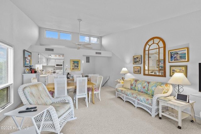 carpeted living room featuring a high ceiling, sink, and ceiling fan